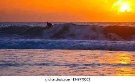 Cool Tourist On Surfboard Carving Dangerous Deep Blue Breaking Wave At Sunrise. Easygoing Fit Male Riding Awesome Ocean Waves On A Sunny Day On Exotic Island. Active Surfer Having Fun On Surfboard.