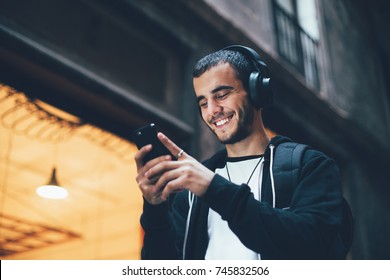 Cool trendy young millennial from generation z laughs and smiles on camera, walks outside with smartphone and big wireless headphones, enjoys new technology and immersive reality - Shutterstock ID 745832506