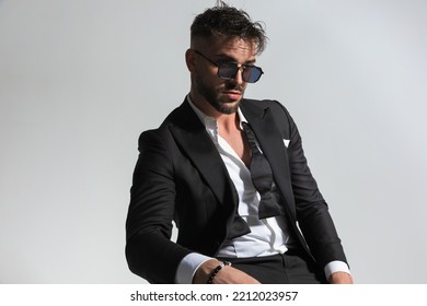 Cool Unshaved Guy Wearing His Collar Shirt Open And Looking Away In Front Of Grey Background In Studio