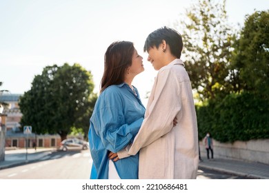 Cool And Young Asian Couple Walking In The City Of Madrid And Kissing.