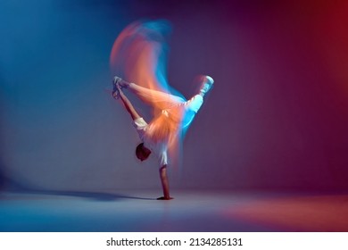 Cool young breakdancer dancing hip-hop in neon studio light, standing on hand. Dance school advertising. Long exposure