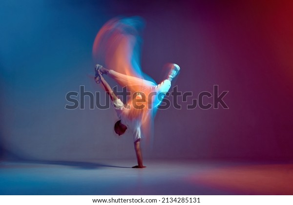 Cool young\
breakdancer dancing hip-hop in neon studio light, standing on hand.\
Dance school advertising. Long\
exposure