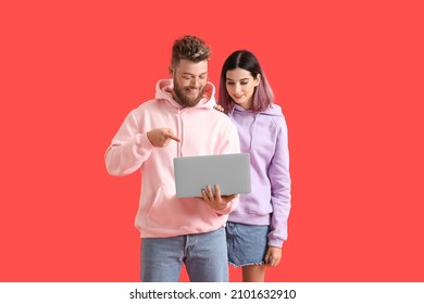 Cool young couple in hoodies and with laptop on color background - Powered by Shutterstock