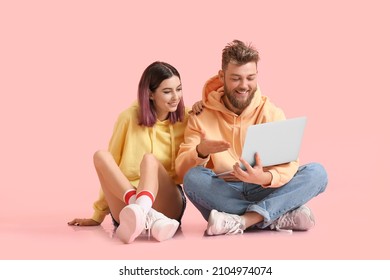 Cool young couple in hoodies and with laptop on color background - Shutterstock ID 2104974074