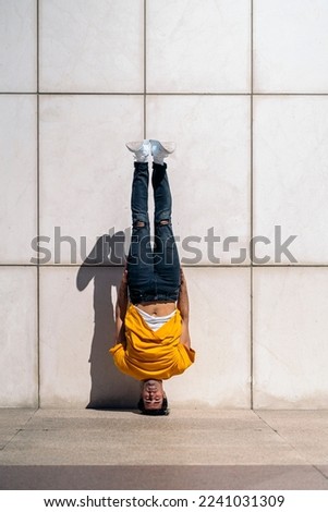 Similar – Man practicing yoga, handstand against a yellow wall