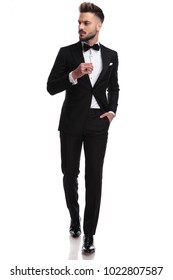 Cool Young Man In Tuxedo Wearing Ring Is Walking And Looks To Side , Isolated On White Background