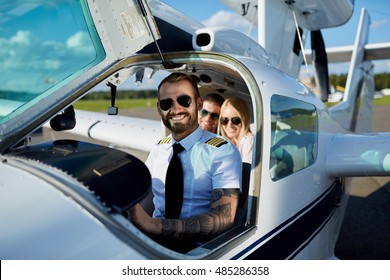 Cool Young Pilot And Happy Couple Sitting In Cabin Of Private Air Plane To Fly On A Vacation This Summer