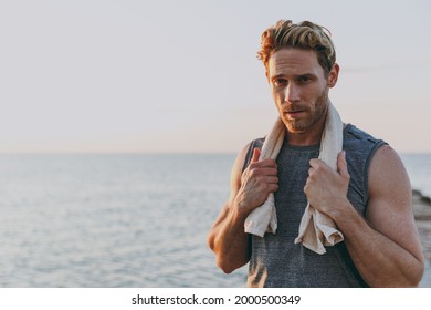 Cool young strong sporty athletic toned fit sportsman man 20s in sports clothes towel warm up training looking camera at sunrise sun dawn over sea beach outdoor on pier seaside in summer day morning. - Powered by Shutterstock