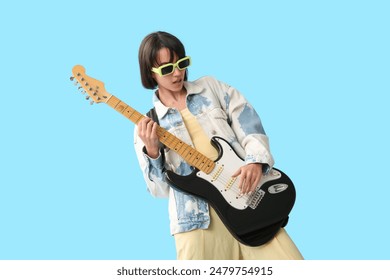 Cool young woman playing electric guitar on blue background - Powered by Shutterstock