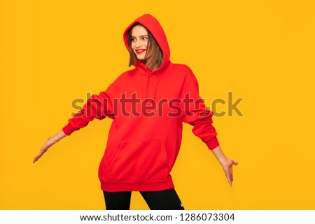 cool young woman posing with a red hoodie, hipster woman on yellow background