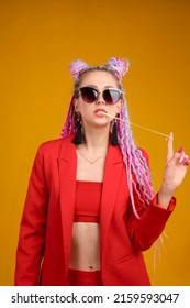 Cool young woman in sunglasses with chewing bubble gum. Studio portrait, arrogant emotion. Red jacket costume and yellow background, colorful person, Afro braids and dreadlocks, hair locks style. - Shutterstock ID 2159593047