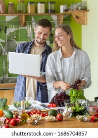 Coolinary Online School. Happy Vegetarian Couple Studying To Cook Healthy Vegetarian Food With Laptop