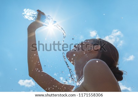 Cooling off in the summer heat. Female runner splashing bottle of water on face.