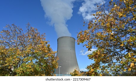 Cooling Tower Of A Nuclear Power Plant. There Is Vapor Rising Out Of It. It Is Surrounded By Trees With Colorful Foliage In Autumn. Symbol Of Electricity Production Before Winter And Energy Crisis. 