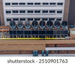 Cooling towers in data center building. Air conditioning cooling towers in front of building with fins to the front. Industrial cooling towers or air cooled water chillers with piping system.