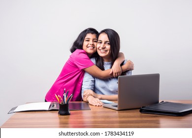 Cooperating Cute Little Indian Girl Hugging Mother While She Is Busy Working From Home Office With Laptop At Desk