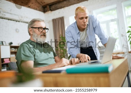 Cooperation of adults and youngsters. Young man helping senior businessman with technological issues on laptop. Concept of business, age diversity, education, modernity, innovations, assistance