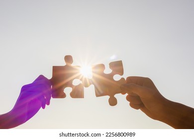 Cooperation Hands holding piece of blank jigsaw puzzle at sunset background - Shutterstock ID 2256800989