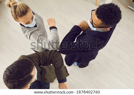 Cooperation, international teamwork, corporate unity concept. Multiethnic Business people partners teammates in medical protective face masks doing elbow bump in office at quarantine, top view
