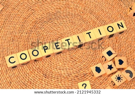 COOPETITION word text from wooden cube block letters on braided rattan mats background. Coopetition is a neologism coined to describe cooperative competition.