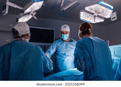 A coordinated team of surgeons meticulously working together under the bright lights of an operating room, equipped with organized surgical tools and instruments, showcasing their expertise. - Powered by Shutterstock