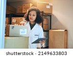 Coordinating the stock control process with smart technology. Shot of a young woman using a digital tablet while doing inventory in the storeroom of a pharmacy.