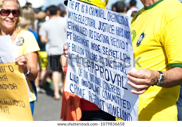 Copacabana beach,\
Rio de Janeiro - July 31, 2016: A demonstrator displays a banner\
protesting against the Brazilian Workers Party and the government\
of President Dilma\
Rousseff