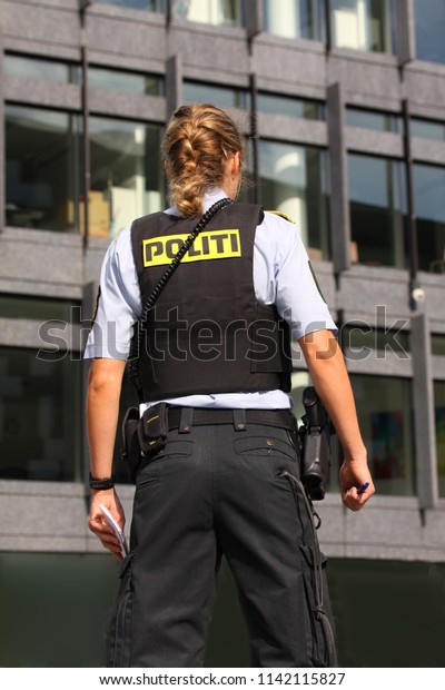 Copenhagen. Denmark - July 24, 2018: Female\
Danish police officer woman standig with notepad and firefighter\
van in background
