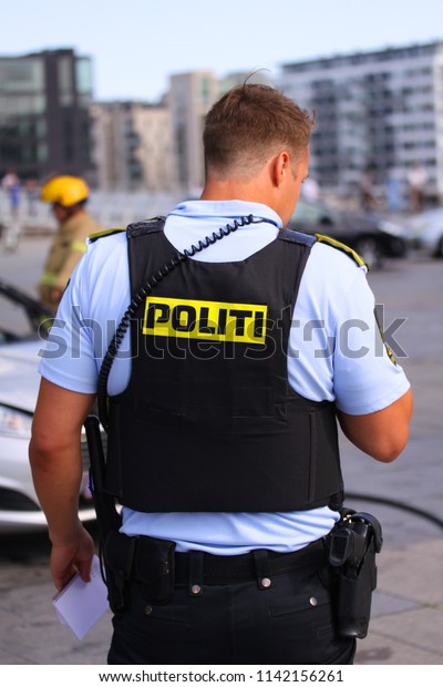Copenhagen. Denmark - July\
24, 2018: Danish police officer supervising traffic and firefighter\
in background