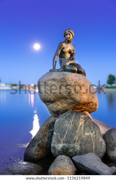 Copenhagen,\
Denmark - June 27, 2018: The Little Mermaid (Danish: Den lille\
Havfrue) by the waterside at the Langelinie promenade at night. It \
is a bronze statue by Edvard Eriksen.\
