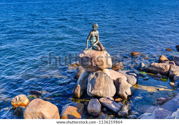 Copenhagen,\
Denmark - June 28, 2018: The Little Mermaid (Danish: Den lille\
Havfrue) on a rock by the waterside at the Langelinie promenade. It\
 is a bronze statue by Edvard Eriksen.\
