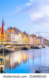 Copenhagen, Denmark – March 24 2022: Nyhavn, touristic place in Copenhagen, pier with colorful houses and boats full of tourists enjoying a sunny day