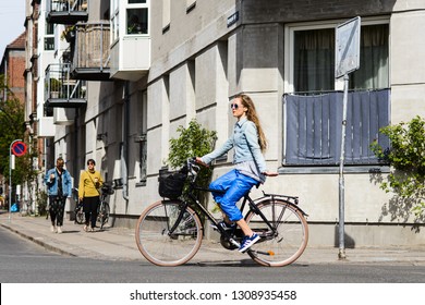 COPENHAGEN; DENMARK - MAY 04; 2018: Young Woman Riding Bicycle Showing Left Turn Signal With Her Hand. Street Style