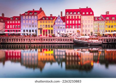 Copenhagen, Denmark. Nyhavn, Kobenhavn's iconic canal, reflects colorful buildings and glowing streetlights at twilight, creating a picturesque tourist destination.