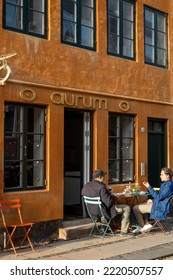 Copenhagen, Denmark Oct 29, 2022 Two Men Sitting Outside A Shop On Dronningensgade  In Christianshavn Enjoying A Meal In The Sun.