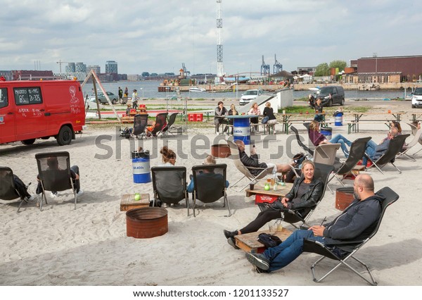 COPENHAGEN, DENMARK - SEPT 7: Relaxing people at\
lounge area of riverside street market Reffen, urban space for\
start-ups and leisure on 7 September, 2018. Copenhagen has\
population near 1.3\
million