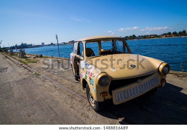 Copenhagen, Zealand / Denmark\
- August 24 2019: A vintage car standing on a shore by the river\
with colorful stickers on it in Reffen street food market. Street\
art.  
