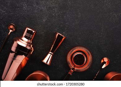 Copper bar tools and accessories for making cocktail. Shaker, jigger, strainer, spoon. Alcohol drinks and beverages preparation concept. Black background, top view, copy space