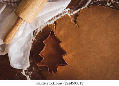 Copper Christmas tree cookie cutter on gingerbread cookie dough with a wood rolling pin and copy space - Powered by Shutterstock