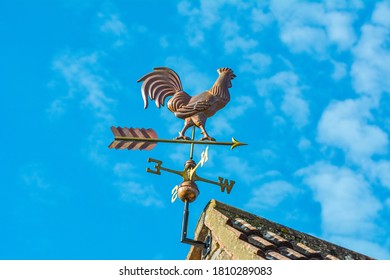 Copper cockerel, rooster or chicken weather vane on a farm with blue sky background