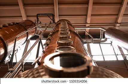 Copper columns stand tall to whiskey still in an American whiskey distillery.