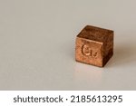 Copper cube with element name Cu on it on cream background