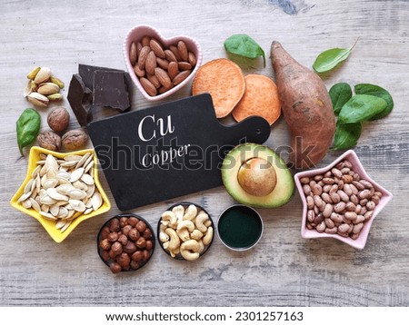 Copper high food. Natural food sources of copper with chemical symbol Cu. Assortment of fresh fruit, vegetable, nuts, seeds high in copper. Dark chocolate, avocado, spirulina, nut, seed, sweet potato