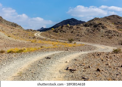 Copper Hike trail, winding gravel dirt road through Wadi Ghargur riverbed and rocky limestone Hajar Mountains in Hatta, United Arab Emirates.  - Powered by Shutterstock