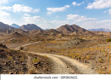 Copper Hike trail, winding gravel dirt road through Wadi Ghargur riverbed and rocky limestone Hajar Mountains in Hatta, United Arab Emirates.  - Powered by Shutterstock
