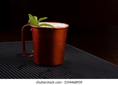 Copper Mug Of Moscow Mule Drink With Mint Leaves Seen From The Front On The Bar Counter In Closeup