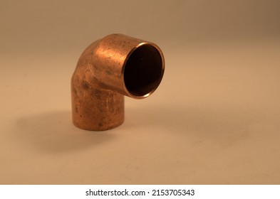 copper pipe elbow joint on tan background.