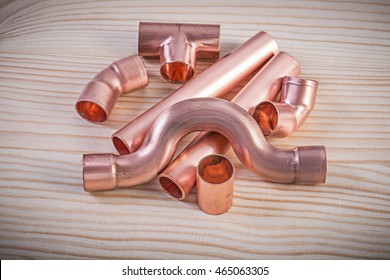 Copper pipe fittings on wooden board plumbing concept.
