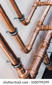 Copper Pipes And Fittings For Carrying Out Plumbing. Copper Pipe In Front Of A White Wall