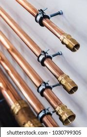 Copper Pipes And Fittings For Carrying Out Plumbing. Copper Pipe In Front Of A White Wall